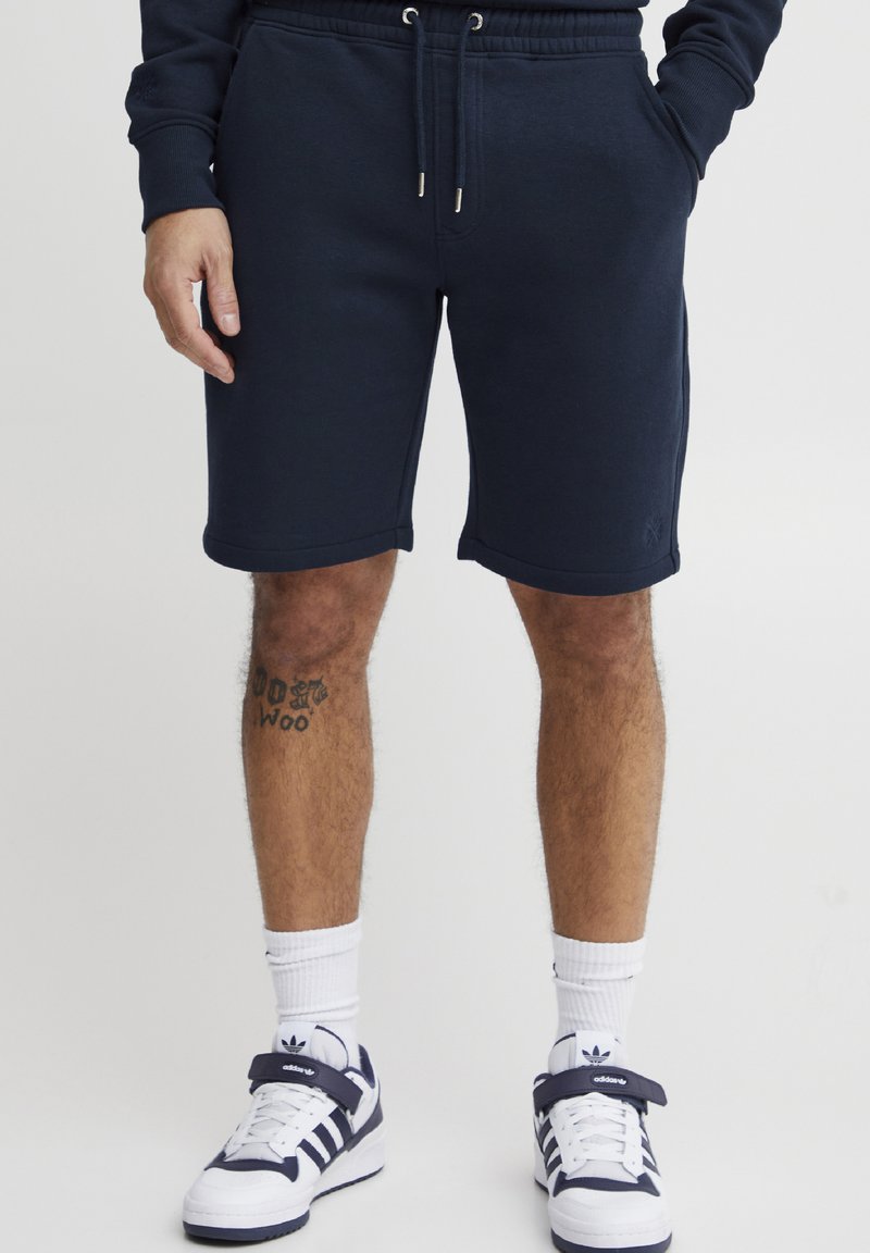 Marineblå bomullsshorts med elastisk midje og snor, med sidelommer og en subtil logo på kanten.