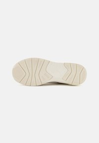 Semelle de chaussure en caoutchouc beige avec un motif de grip texturé. Comprend un cuir segmenté pour une traction et affiche un logo sur le côté.