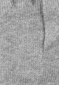 Graues gestricktes Stoff mit einem engen Stichmuster. Die Textur erscheint weich und warm und zeigt einen gleichmäßigen, durchgehenden Faden.