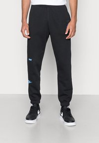 Svarta mjukisbyxor med elastisk midja, med en liten blå logotyp på vänster lår. Tillverkade av mjukt, texturerat tyg; avsmalnande passform.