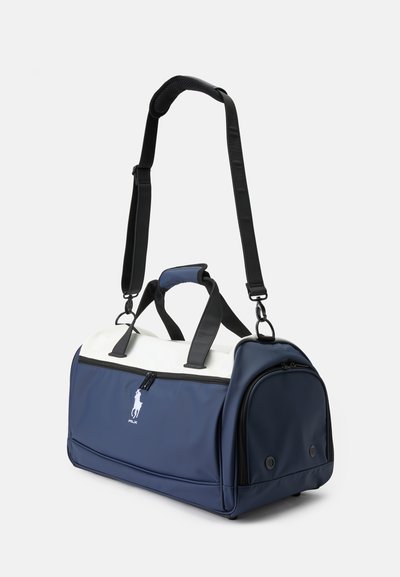 Saco de desporto azul-marinho feito de material durável, com um topo branco, duas alças, uma alça ajustável e um logótipo na frente.