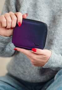 Zippered wallet featuring a gradient from dark blue to purple, made of textured fabric, with a small logo detail at the bottom corner.