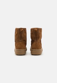 Braune Wildleder Stiefeletten mit weicher Textur, niedrigem Absatz und zwei hinteren Ziehhilfen für ein einfaches Anziehen. Robuste Gummisohlen mit Grip-Muster.