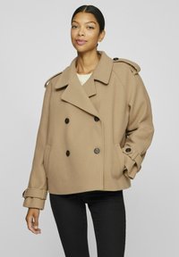 Brun dubbelknäppt sjömansjacka i mjuk ullblandning, med stora knappar, breda slag och justerbara ärmar. Matchad med svarta byxor.