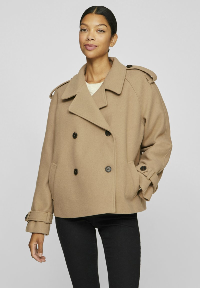 Brun dubbelknäppt sjömansjacka i mjuk ullblandning, med stora knappar, breda slag och justerbara ärmar. Matchad med svarta byxor.