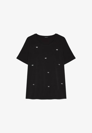 T-shirt nera a maniche corte con scollo rotondo, decorata con piccoli ricami bianchi a forma di fiocco sparsi sul davanti.
