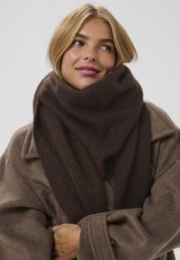 Brun ulderskærf med en blød tekstur, draperet om halsen. Skærfet har en triangular form og er parret med en brun frakke.