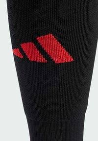 Black sports sock featuring a ribbed texture with a prominent red logo in an abstract geometric design.
