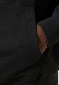 Czarna, bawełniana bluza z kapturem z przednią kieszenią, wykonana z miękkiego materiału o gładkiej fakturze, starannie wykończona.