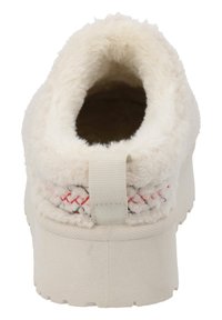 Zapatilla color crema con exterior esponjoso, forro texturizado, acentos rojos cosidos y una pestaña en la parte trasera para ponerlas con facilidad.