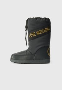 Fekete párnázott csizma, amely húzózsinórral záródik, arany "LOVE MOSCHINO" szalaggal és kör alakú logóval az oldalon. Lapos talp.