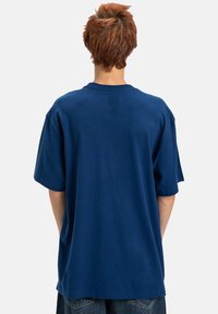 Marinblå bomull T-shirt med avslappnad passform, korta ärmar och rundad hals. Tyget verkar mjukt med minimala sömdetaljer.