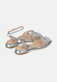 Zilveren metallic sandalen met een vierkante neus, gestrikte ontwerp, versierd met rhinestones, en een lage blokhak voor stabiliteit.