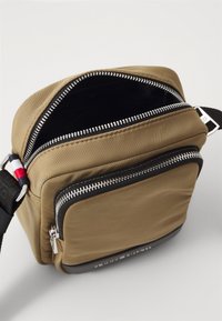 Geantă crossbody din nylon marron cu un fund negru, având deschidere cu dublu fermoar, curea ajustabilă și fără compartimente interioare vizibile.