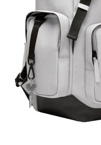 Un sac à dos en tissu gris avec une base noire, doté de plusieurs poches, de bretelles noires et d'un porte-clés avec une clé attachée.