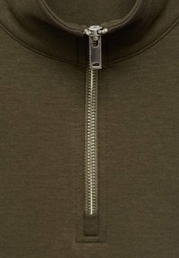 Suéter verde oliva con cremallera, que presenta un cuello alto, textura acanalada y una cremallera metálica. La tela es suave y se ajusta al cuerpo.