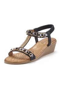 Zwarte wedge sandalen met een T-band ontwerp, gouden kettingaccenten en een zachte, gestructureerde binnenzool. Beschikt over een elastische band en een stevige hak.