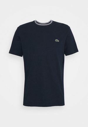 Marineblaue T-Shirt mit kurzen Ärmeln, weiß-navy gestreiftem Rundhalsausschnitt und kleinem grünen Krokodil-Logo auf der linken Brust.