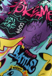 Tissu coloré avec des textes de style graffiti comme "EXTREME", "Prêt pour la bataille" et des visages de dessin animé aux accents violets, jaunes, bleus et noirs vibrants.