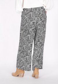 Pantaloni a gamba larga in bianco e nero con motivo paisley, dotati di una vita comoda, tessuto morbido e taglio alla caviglia. Accoppiati con stivali alla caviglia color nocciola.