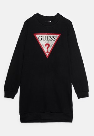 Svart sweatshirtklänning med en stor röd och vit triangel-logotyp med texten "GUESS?", tillverkad av mjukt material med ribbade ärmslut.