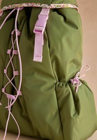 Groene gevoerde rugzak met roze banden, kantdetails en bloemenrand. Voorzien van een strakkere sluiting en verstelbare zijsluiting.