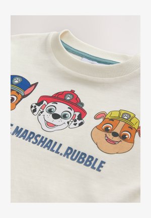 Kremas džemperis, kuriame pavaizduoti animacinių filmų šunų personažai ryškiomis spalvomis: raudonos ir geltonos kepurės, juodi taškeliai ir ryškūs veido bruožai. Po personažais yra tekstas.