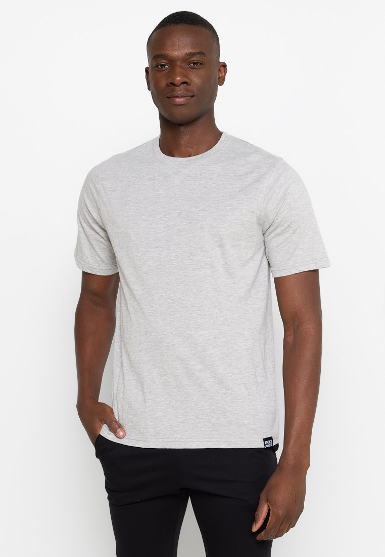 Hellegraues Rundhals-T-Shirt aus Baumwolle. Kurze Ärmel, lockere Passform, mit einem kleinen schwarzen Logoetikett an der Seite. Glatte Textur.