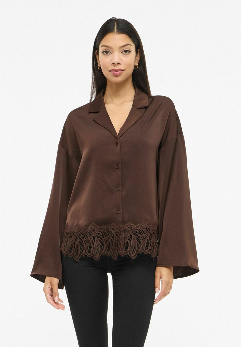 Brun langermet skjorte i sateng med hakket krage og knappelukking foran, med intrikat blonde detalj ved kanten.