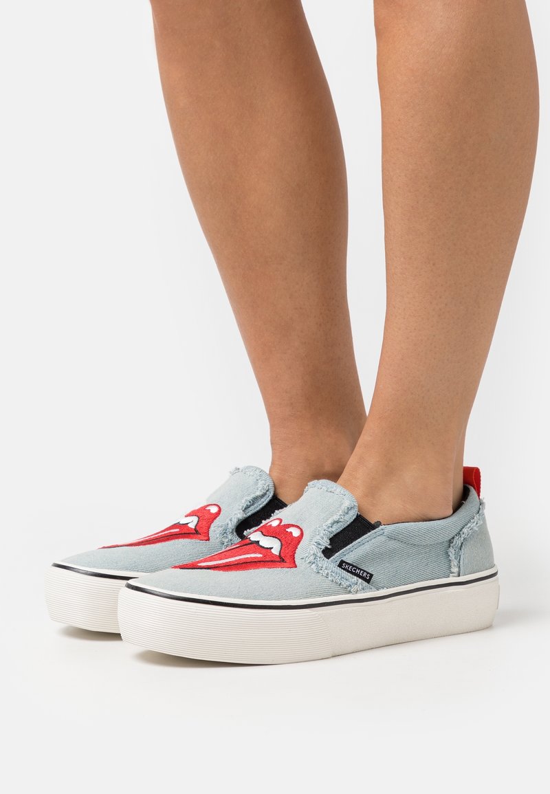 Světlomodré slip-on tenisky s grafikou červených rtů, odřenými okraji, elastickými bočními panely a bílými gumovými podešvemi. Logo viditelné na boku.