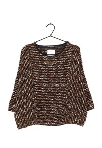 Maglione lavorato a maglia con una vestibilità ampia e morbida. Motivo zigzag marrone e bianco, scollatura rotonda, maniche 3/4, appeso a un gancio nero.