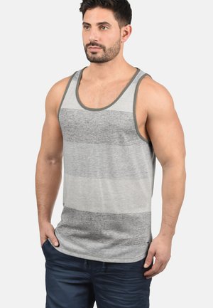 Débardeur rayé gris et blanc avec un col rond et des finitions contrastantes. Le tissu semble doux ; le design est à la fois décontracté et ajusté, avec une coupe droite.