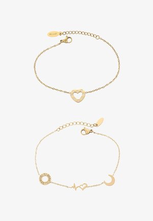 Kaksi kultaranneketta: toinen, jossa on sydänriipus koristeena strassikivillä; toinen sisältää symboleita, kuten ympyrä, sydämen syke, sydän ja kuu.