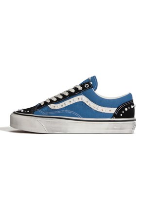 Blauwe en zwarte lage sneaker met witte zool, witte veters en decoratieve witte parels langs de zijstreep en hiel.