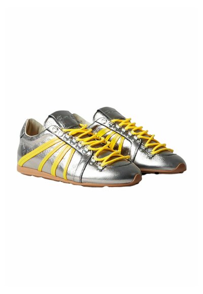 Scarpe sportive metalliche argento con lacci e dettagli gialli, caratterizzate da una superficie liscia, suole in gomma e un design a profilo basso.