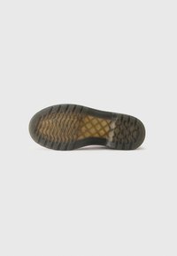 Suela de zapato con un material de goma, que presenta una superficie texturizada negra y un dibujo en la plantilla para mejorar el agarre y la durabilidad.