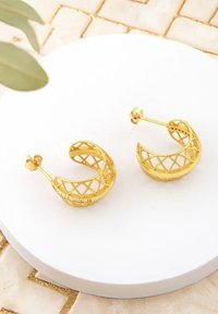 Guldörhängen i form av ringar med en intrikat gallerdesign och texturerade detaljer, med en gångjärnsstängning för säker användning.