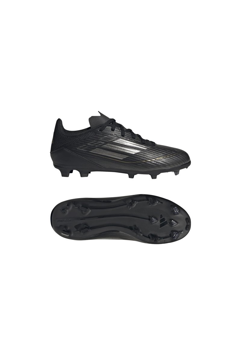 Botas de fútbol negras con un upper texturizado, diseño elegante y suela con tacos. La superficie tiene rayas sutiles y un perfil bajo.