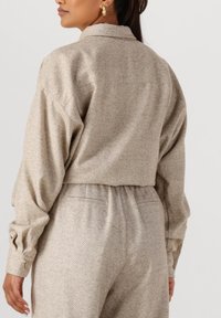 Beige herringbone-patroon overhemd- en broekset, met een relaxte pasvorm, textuurstof met subtiele glans, en knoopmanchetten.