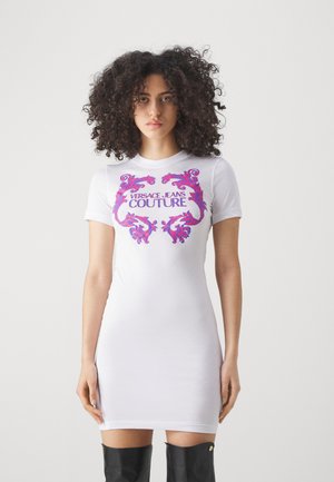 Abito in cotone bianco con maniche corte, caratterizzato da una grafica floreale dai toni vivaci di rosa e viola e testo "VERSACE JEANS COUTURE".