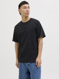 Schwarzes Baumwoll-T-Shirt mit rundem Ausschnitt und kurzen Ärmeln, das einen lässigen Schnitt hat. Getragen mit blauen Denim-Shorts. Glatte Textur.