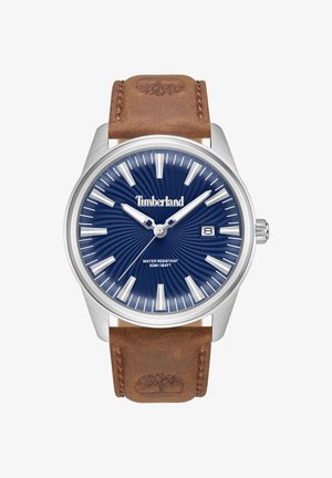 Zegarek Timberland z kopertą ze stali nierdzewnej, niebieską tarczą z wzorem słonecznym, srebrnymi znacznikami godzinowymi oraz brązowym skórzanym paskiem.