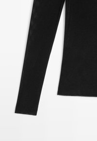 Czarna bluzka z długim rękawem o lekkiej, gładkiej fakturze, dopasowanym kroju i prostym dole. Prosta i uniwersalna, bez dodatkowych zdobień.