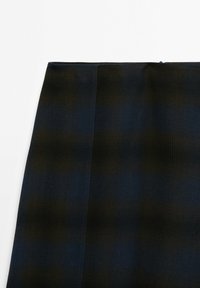 Jupe à carreaux bleu foncé et noire avec une texture lisse, une forme structurée, un ourlet soigné et une fermeture éclair dissimulée.