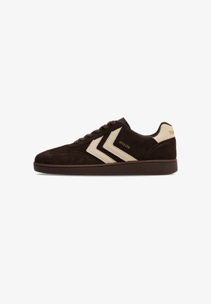 Donkerbruine suède sneaker met crèmekleurige chevronstrepen, bijpassend hielstuk, bruine zool en tekst "VM78 CPH" aan de zijkant.
