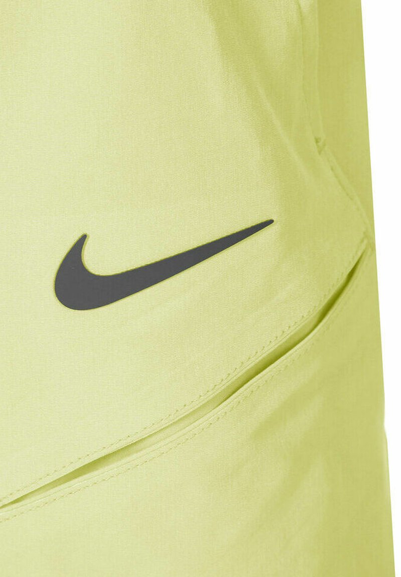 Szorty sportowe Nike w jaskrawej zielonej tkaninie, z czarnym logo swoosh. Materiał ma gładką teksturę i zapinane na zamek kieszenie.