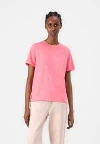 Roze katoenen t-shirt met een ronde hals en korte mouwen. Heeft een losse pasvorm en zijsplitten voor bewegingsgemak.