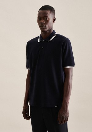 Marineblå polo skjorte med hvid krave og ærme accenter, lavet af tekstureret stof. Har en knaplukning og et lille brandlogo ved kanten.