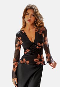 Schwarzes Oberteil mit langen, durchsichtigen Ärmeln im floralen Muster in verschiedenen Orangetönen. V-Ausschnitt und figurbetonte Passform mit einem Peplum-Saum.