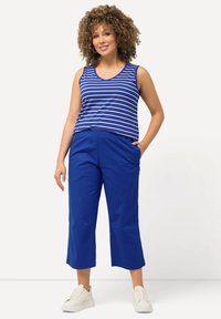 Blå och vit randig linne med V-ringning, tillsammans med enfärgade blå capribyxor. Outfiten har en avslappnad passform och mjukt tyg.